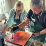 Two women painting on a lotus leaf.